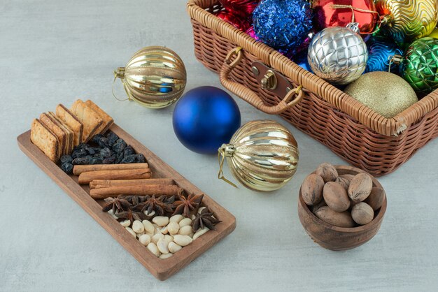 Christmas festive balls with wooden plate of cinnamon sticks, star anise on white background. High quality photo
