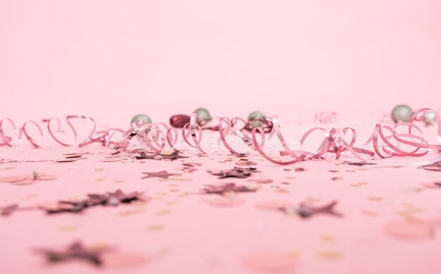 Christmas festive pink background with serpentine and festive toys.