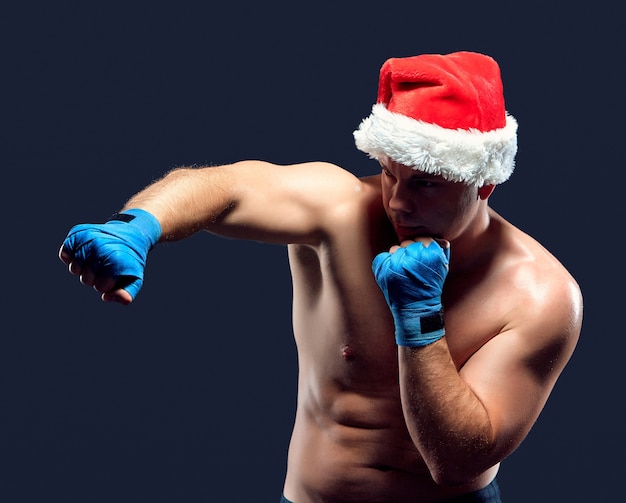 Free photo christmas fitness boxer wearing santa hat boxing on black