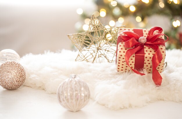 Christmas gift with decorations on the tree on a light blurred bokeh background copy space.