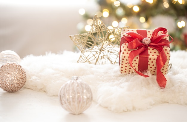 Christmas gift with decorations on the tree on a light blurred bokeh background copy space.