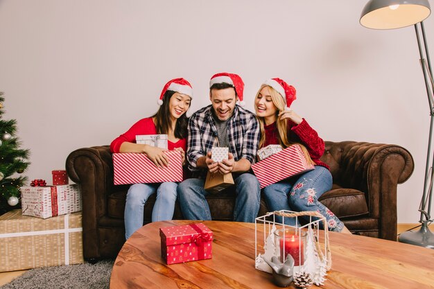 Концепция рождественского подарка с молодыми друзьями на диване