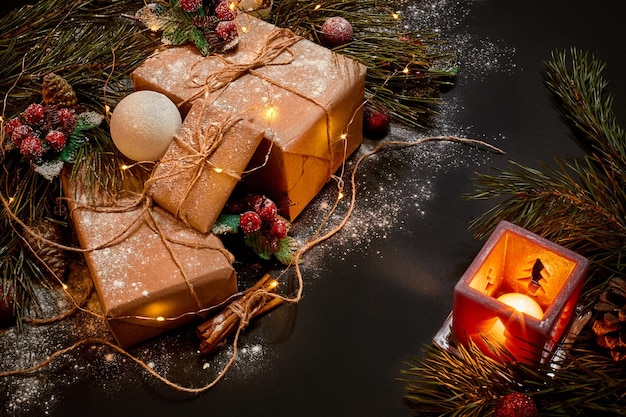 Christmas gifts and red candlestick near green spruce branch on a black background. Christmas background. Top view.