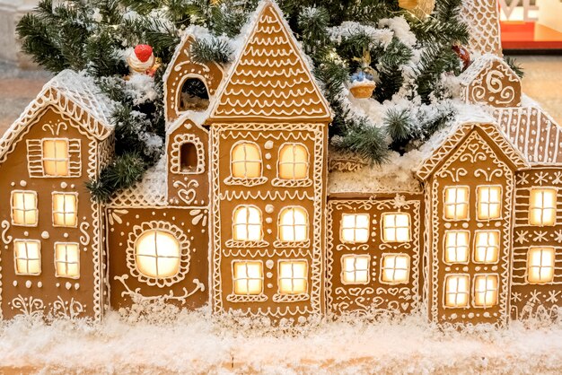 Christmas gingerbread houses with light from the windows standing in a row holiday background