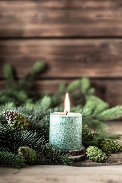 Christmas green candle with fir branches and cones on wooden table