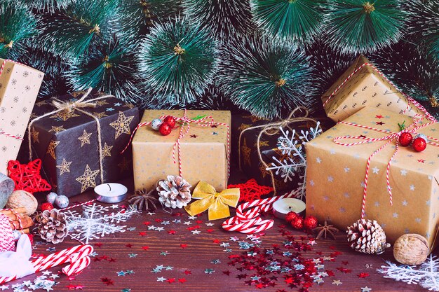 Новогодняя праздничная подарочная коробка на украшенном снегом праздничном столе с сосновыми шишками еловыми ветками
