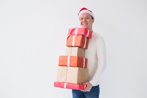 クリスマス​休暇​と​白い​背景​の​上​の​たくさん​の​贈り物​を​保持している​サンタ​の​帽子​の​コンセプト​の​人​を​提示します​。
