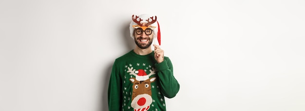 Foto gratuita concetto di natale e festività uomo sorridente con il cappello di babbo natale che sembra felice tenendo la maschera da festa per