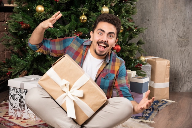 Christmas, holidays and people concept - happy man with gift box at home.