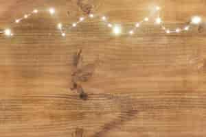 Free photo christmas lights on top on wooden background.