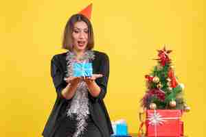 Free photo christmas mood with beautiful lady holding gift happily in the office on yellow