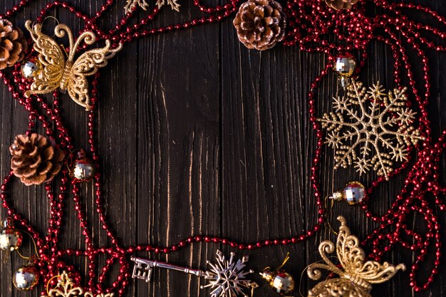クリスマスまたは新年のフレーム。クリスマスの枝、モミの実、木の板の赤いネックレス