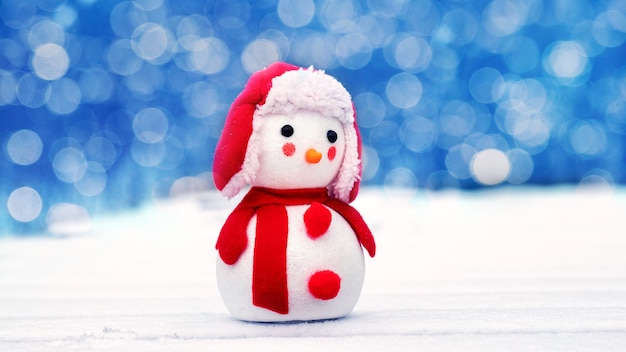 Christmas and new year greeting card with snowman outdoors and bokeh in the background