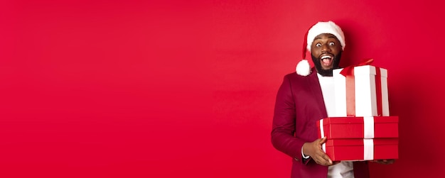 Christmas new year and shopping concept cheerful black man secret santa holding xmas presents and sm