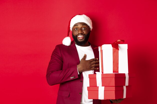 크리스마스, 새해 및 쇼핑 개념입니다. 크리스마스 선물을 받는 행복한 흑인 남자