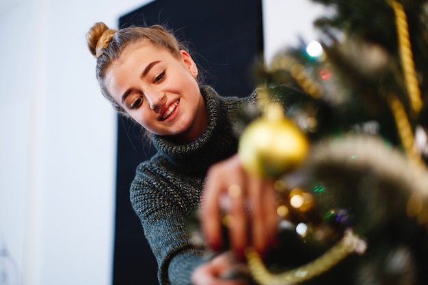 クリスマスと新年の雰囲気。セーターの魅力的な若い女性は準備をしなさい