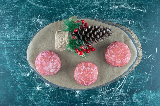 Christmas ornament and cookies on a board on blue.