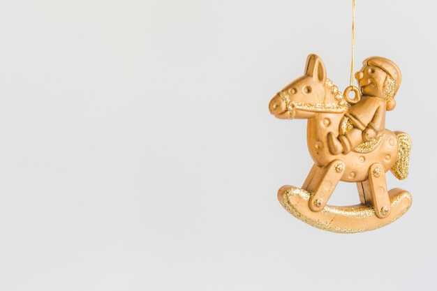 Foto gratuita ornamento di natale con la figurina dorata che si siede sul cavallo a dondolo contro fondo bianco