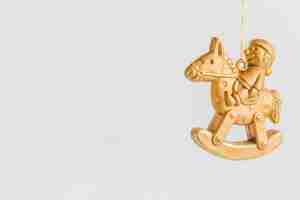 Foto gratuita ornamento di natale con la figurina dorata che si siede sul cavallo a dondolo contro fondo bianco