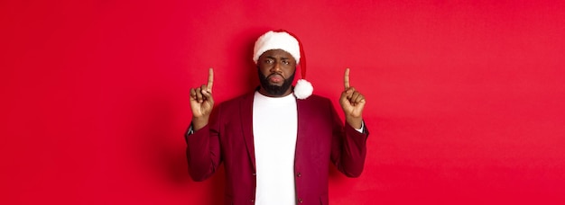 크리스마스 파티와 휴일 개념은 비참하고 슬픈 아프리카계 미국인 남자가 손가락으로 위를 가리키는