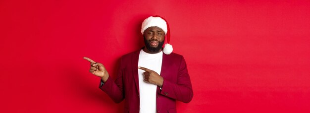 Free photo christmas party and holidays concept skeptical and unamused black man looking with disdain pointing