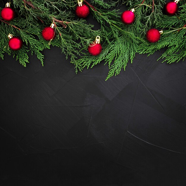 Copyspaceと黒の背景に赤のボールで飾られたクリスマスパインの葉