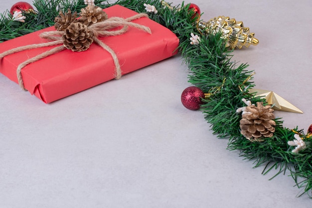 無料写真 灰色のテーブルに赤いボックスが付いたクリスマスの松ぼっくりのおもちゃ。