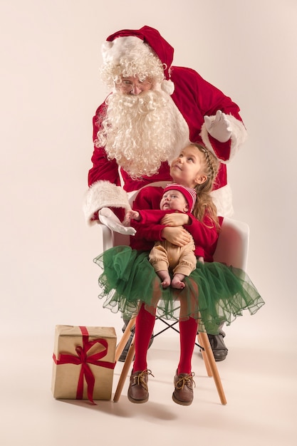귀여운 신생아 아기 소녀, 예쁜 사춘기 자매의 크리스마스 초상화, 선물 상자 크리스마스 옷과 산타 클로스를 입고