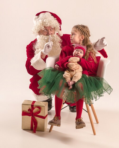 Christmas portrait of cute little newborn baby girl, pretty teen sister, dressed in christmas clothes and Santa Claus with gift box