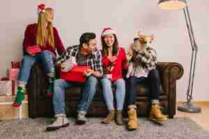 Free photo christmas present concept with friends sitting on couch