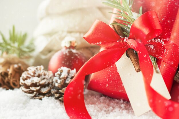 Рождественские подарки или подарки с элегантными лук и рождественские украшения на ярком снежном фоне, рождественская концепция