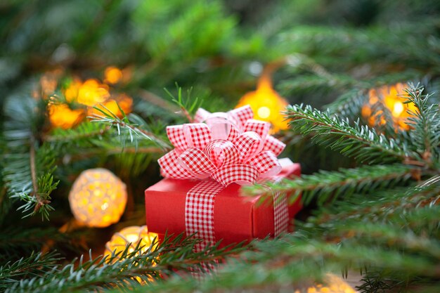 Christmas red gift box with red bow in fir branches. merry christmas and happy new year composition.