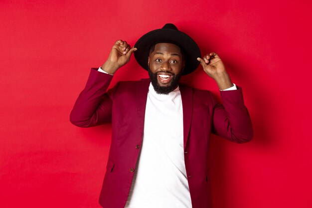 Christmas shopping and people concept. Happy Black man having fun on party, smiling happy at camera, red background.