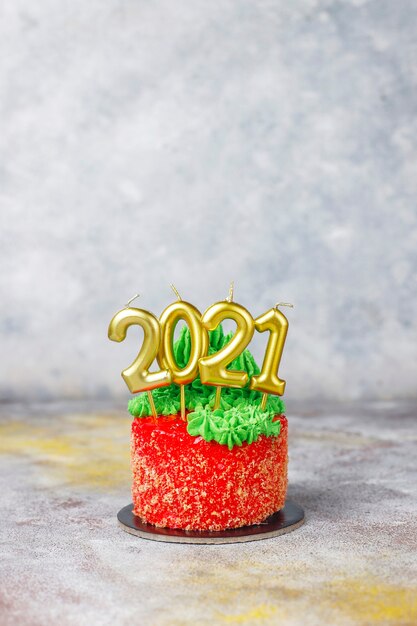 クリスマスツリー、サンタクロース、キャンドルの甘い数字で飾られたクリスマスの小さなケーキ。