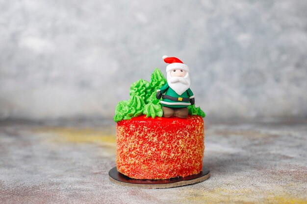 Christmas small cake decorated with sweet figures of christmas tree,santa claus and candles.