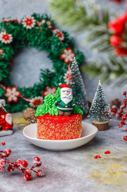 Christmas small cake decorated with sweet figures of christmas tree, santa claus and candles.