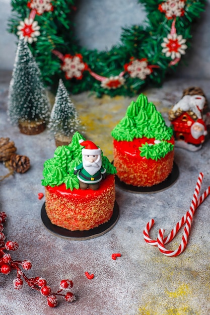 Christmas small cake decorated with sweet figures of christmas tree, santa claus and candles.