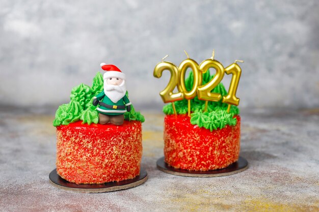 Free photo christmas small cake decorated with sweet figures of christmas tree, santa claus and candles.