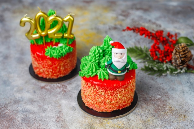 クリスマスツリー、サンタクロース、キャンドルの甘い数字で飾られたクリスマスの小さなケーキ。