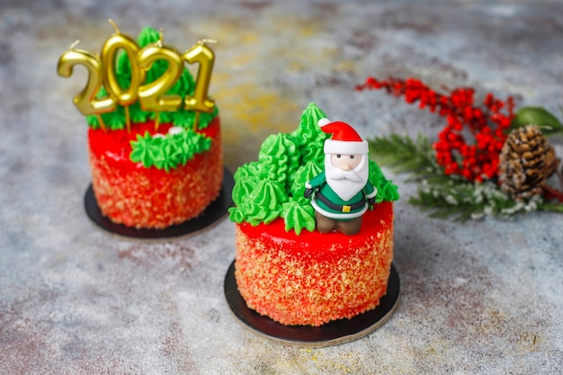 Christmas small cake decorated with sweet figures of christmas tree, santa claus and candles.