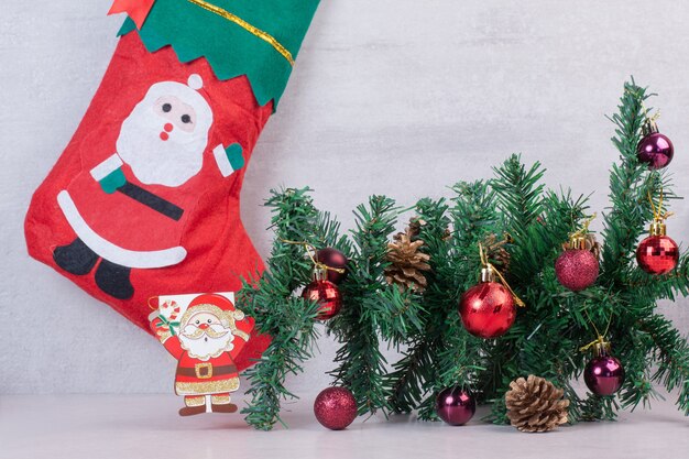 Рождественский носок, полный праздничных шаров на белой поверхности