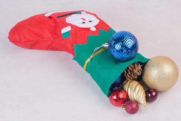 Рождественский носок, полный праздничных шаров на белой поверхности