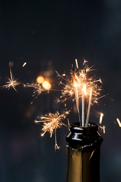 Free photo christmas sparkler in champagne bottle at night