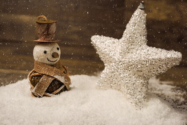 Christmas star and snowman on wooden board with snow