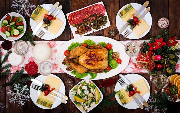 Christmas table isserved with a turkey, decorated with bright tinsel and candles