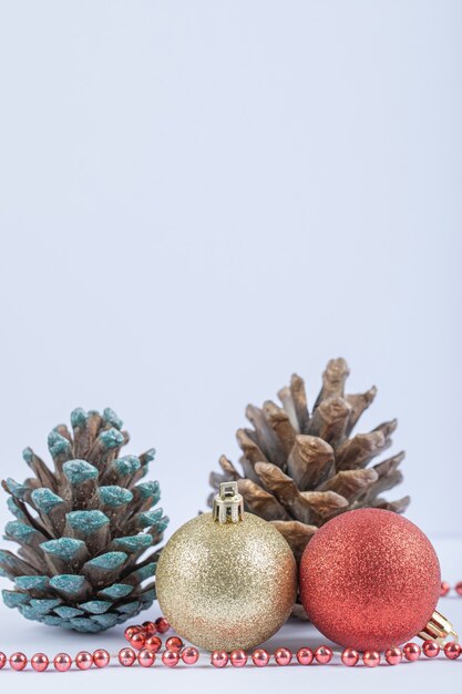 Christmas tree balls and oak cones with red pearl chain on the white