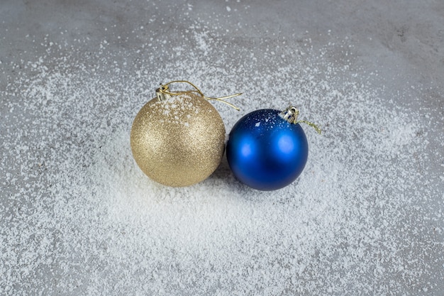 Christmas tree decor balls sitting on a pile of coconut powder on marble surface