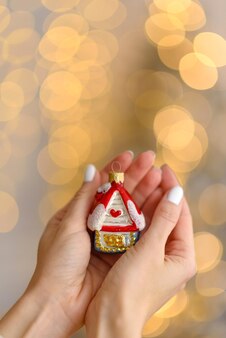 아름다운 여성의 손에 있는 집 모양의 크리스마스 트리 장식. 크리스마스 준비