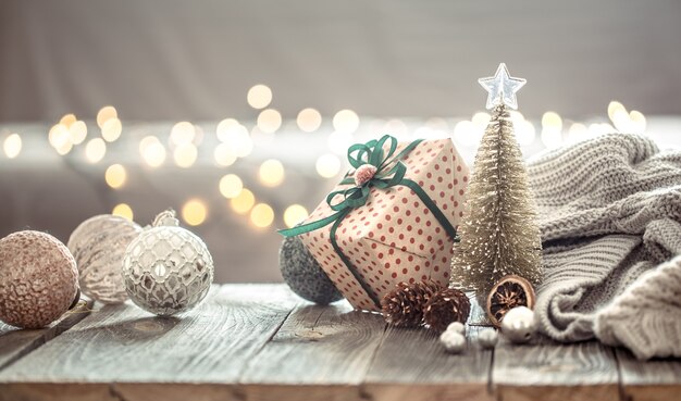 壁にセーターと装飾が施された木製のテーブルの上のクリスマスライトボケの上のクリスマスツリーの装飾。