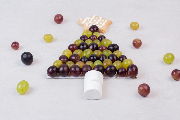 Free photo christmas tree made of grapes, cookie and marshmallows .